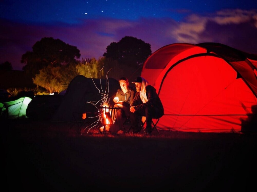 Campers by a campfire and tent at night